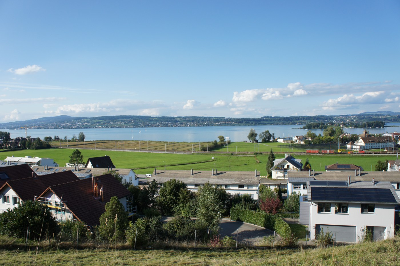 友人の家の近くから見わたした、チューリッヒ湖(Zürichsee)ののどかな眺め。ゆるやかな丘に家々が点在し、その先に湖と対岸の街並みが広が
